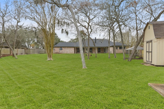 view of yard with a storage shed, an outbuilding, and fence