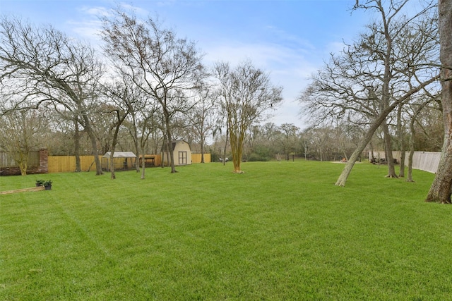 view of yard featuring an outbuilding, a storage shed, and fence