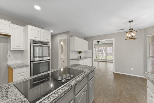 kitchen featuring wood finished floors, visible vents, white cabinets, double oven, and black electric stovetop