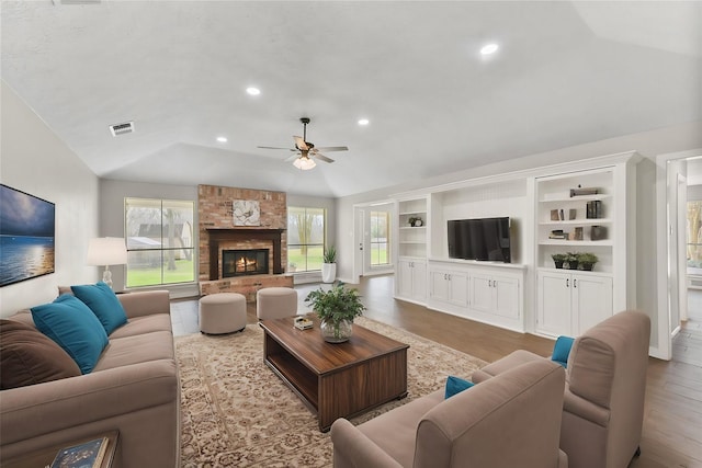 living area featuring recessed lighting, visible vents, a stone fireplace, and wood finished floors