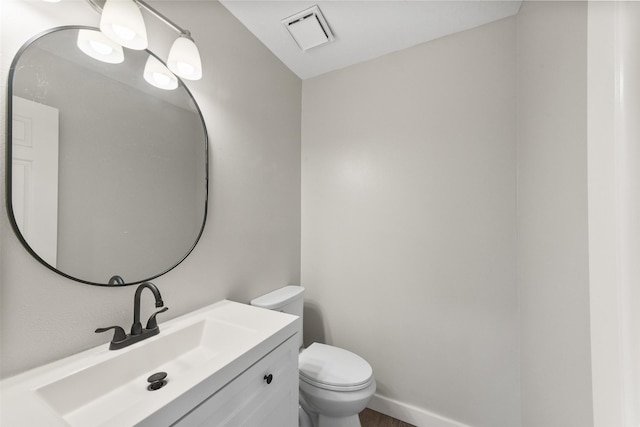 half bathroom featuring visible vents, baseboards, toilet, and vanity