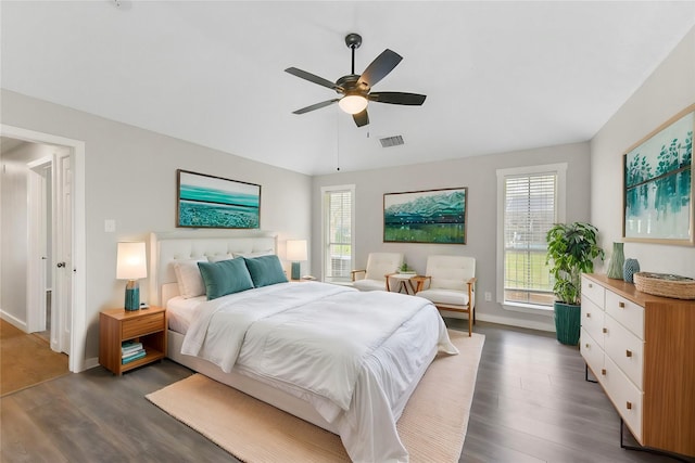 bedroom featuring visible vents, baseboards, dark wood finished floors, and a ceiling fan