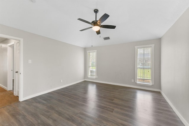 empty room with dark wood-type flooring, plenty of natural light, visible vents, and ceiling fan