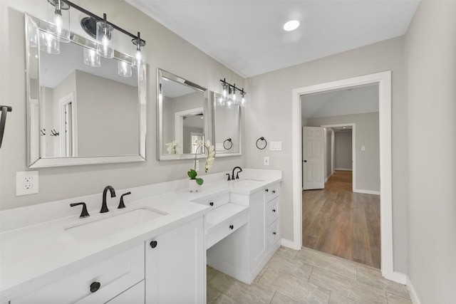 bathroom with a sink, baseboards, and double vanity