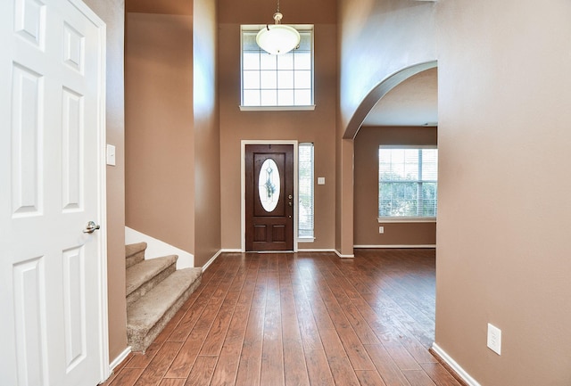 entryway featuring arched walkways, stairway, hardwood / wood-style flooring, and baseboards