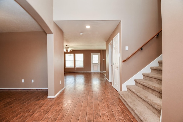 foyer with ceiling fan, arched walkways, wood finished floors, baseboards, and stairs