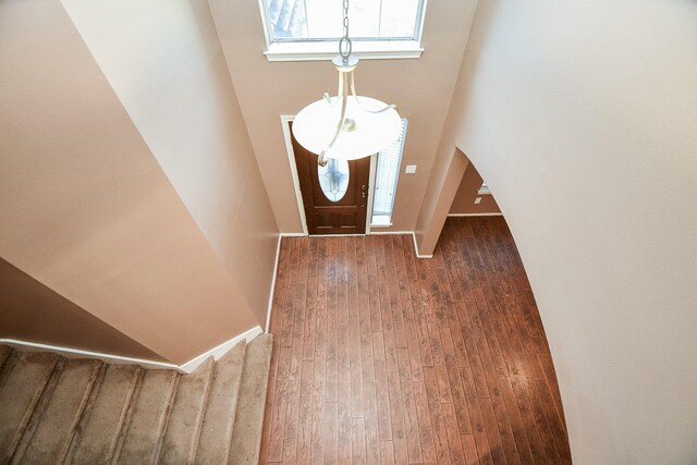 foyer with a skylight, a towering ceiling, baseboards, and wood finished floors