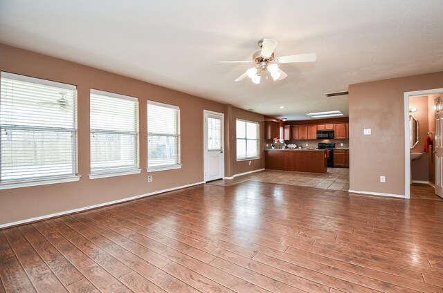unfurnished living room featuring ceiling fan, visible vents, baseboards, and wood finished floors
