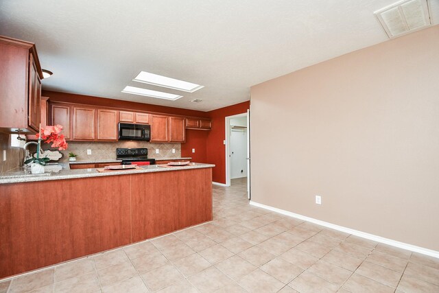kitchen with a peninsula, a skylight, visible vents, decorative backsplash, and black appliances