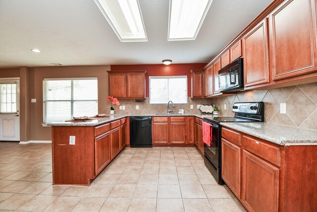 kitchen with black appliances, brown cabinetry, a peninsula, and a sink