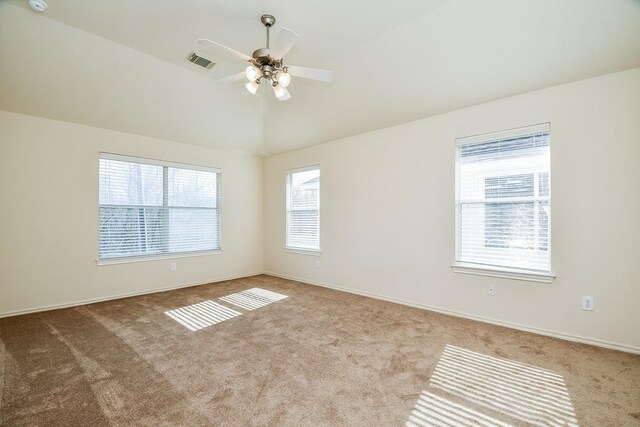 carpeted spare room with vaulted ceiling, ceiling fan, and visible vents