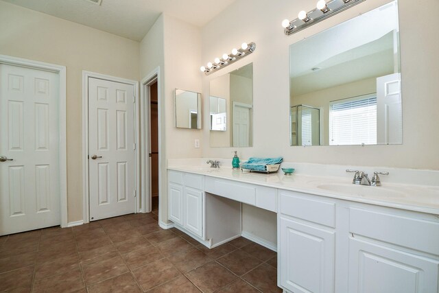 full bathroom featuring double vanity, an enclosed shower, a sink, and tile patterned floors