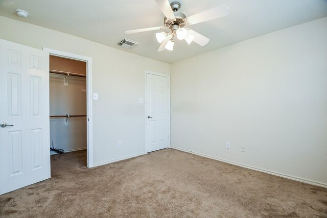 unfurnished bedroom featuring a spacious closet, a closet, carpet, and visible vents
