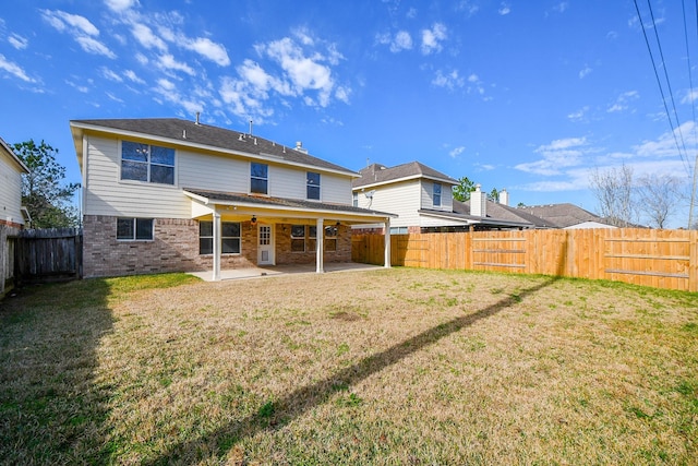 back of property with brick siding, a fenced backyard, a lawn, and a patio