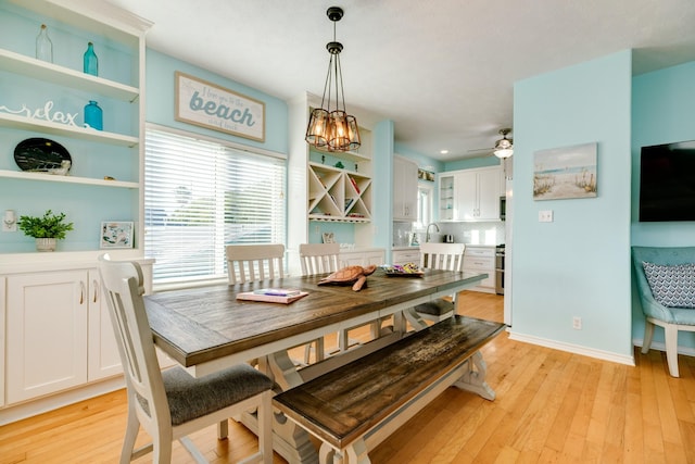 dining room with baseboards, light wood finished floors, and ceiling fan with notable chandelier