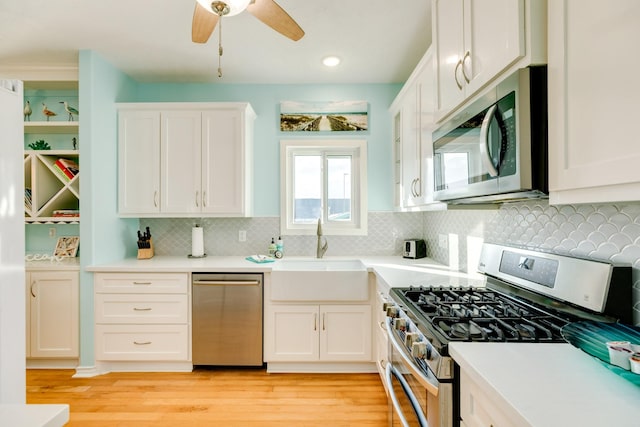 kitchen with light wood-style flooring, stainless steel appliances, a sink, white cabinetry, and light countertops