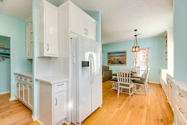 kitchen featuring white fridge with ice dispenser, light countertops, light wood-style flooring, and white cabinets