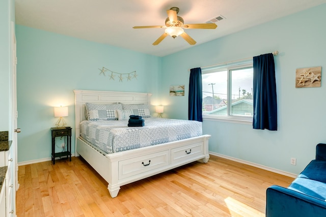 bedroom with a ceiling fan, light wood-type flooring, visible vents, and baseboards