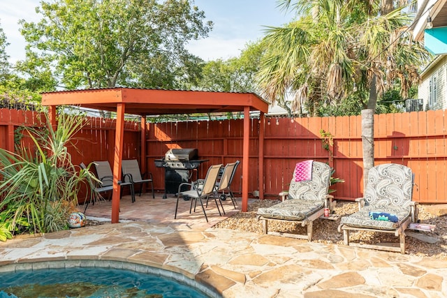 view of patio / terrace with grilling area, a fenced backyard, and a hot tub