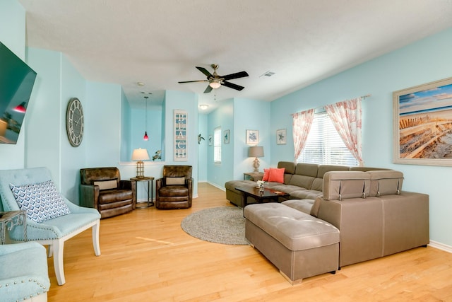 living area featuring light wood-style floors, visible vents, baseboards, and a ceiling fan