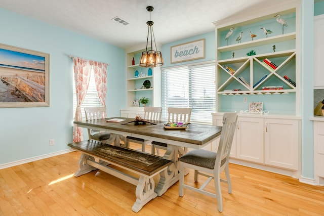 dining area with light wood-style floors, a healthy amount of sunlight, and visible vents