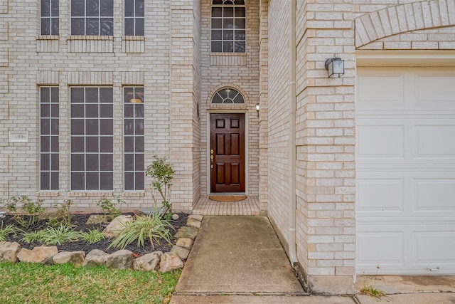 property entrance featuring a garage and brick siding