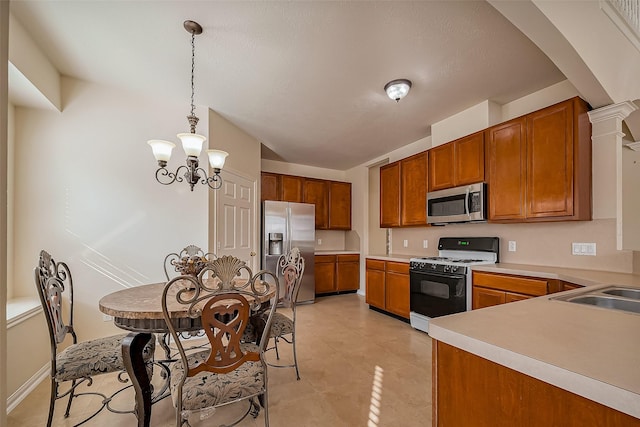 kitchen featuring a chandelier, light tile patterned floors, light countertops, appliances with stainless steel finishes, and brown cabinets