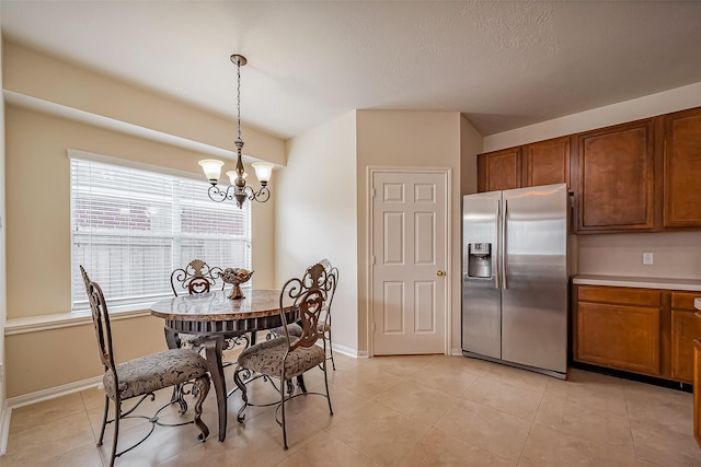 dining area with baseboards, a notable chandelier, and light tile patterned flooring