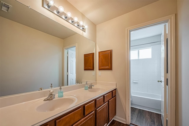 bathroom featuring double vanity, visible vents, a sink, and wood finished floors