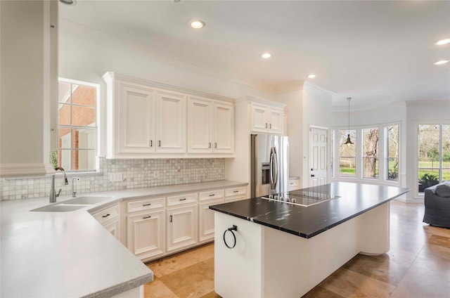 kitchen with black electric stovetop, a sink, stainless steel refrigerator with ice dispenser, backsplash, and a center island