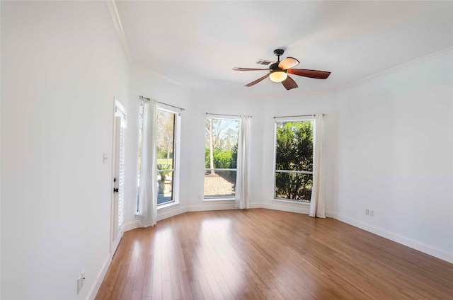 unfurnished room with ornamental molding, light wood-style flooring, baseboards, and a ceiling fan