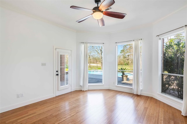 unfurnished room featuring ceiling fan, a healthy amount of sunlight, crown molding, and wood finished floors