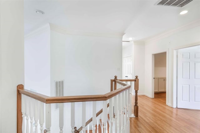 corridor featuring visible vents, light wood-type flooring, an upstairs landing, and crown molding