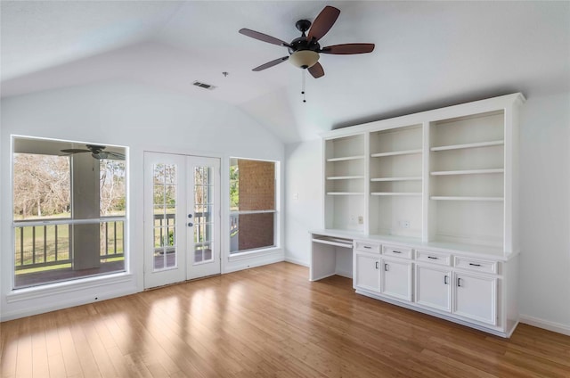 unfurnished living room featuring visible vents, a ceiling fan, built in study area, vaulted ceiling, and wood finished floors