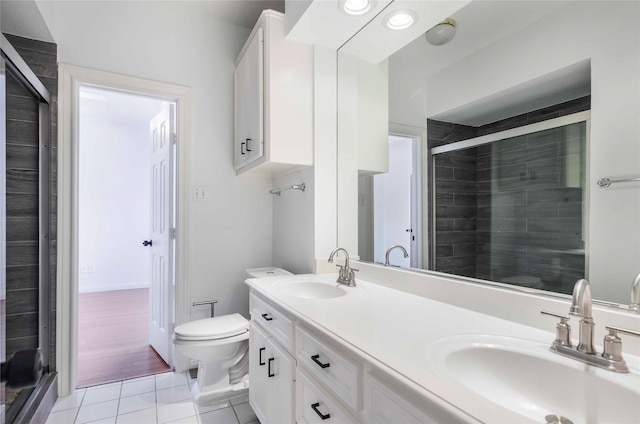 bathroom with toilet, tile patterned flooring, a shower stall, and a sink