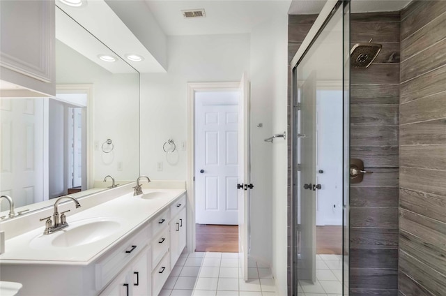 bathroom featuring double vanity, a shower stall, visible vents, and a sink