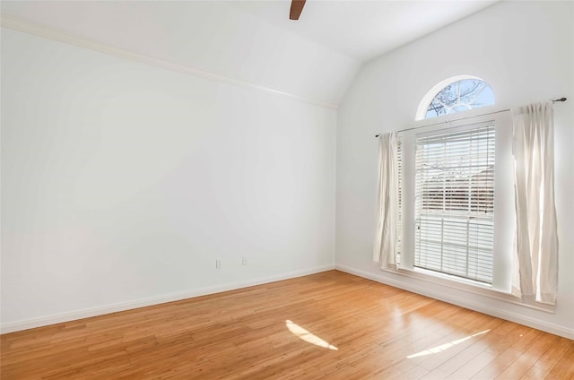 empty room with lofted ceiling, light wood finished floors, ceiling fan, and baseboards