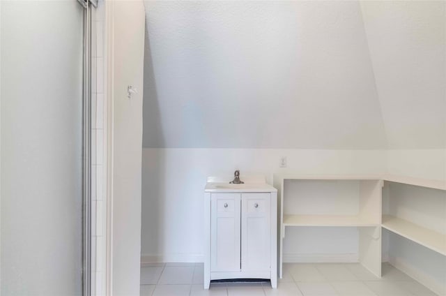 bathroom with lofted ceiling, a sink, baseboards, and tile patterned floors