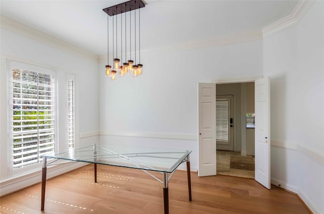 dining space with baseboards, a notable chandelier, ornamental molding, and wood finished floors