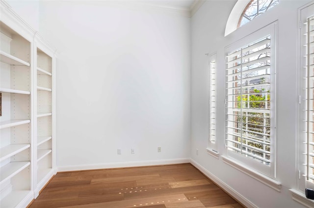 empty room featuring ornamental molding, wood finished floors, and baseboards