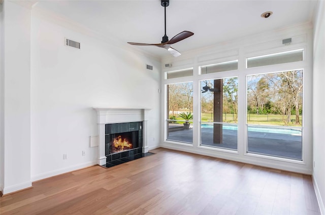 unfurnished living room featuring visible vents, ceiling fan, a fireplace, and wood finished floors