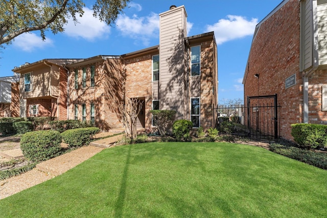 exterior space featuring brick siding, a chimney, fence, and a front yard