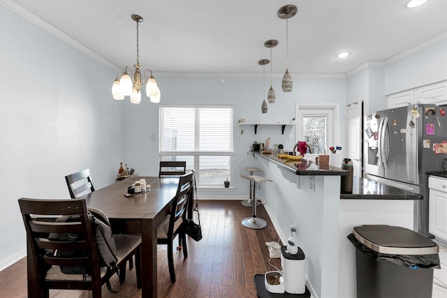 dining space with dark wood-style floors and crown molding