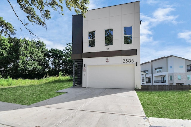 contemporary home featuring a garage, a front lawn, concrete driveway, and stucco siding