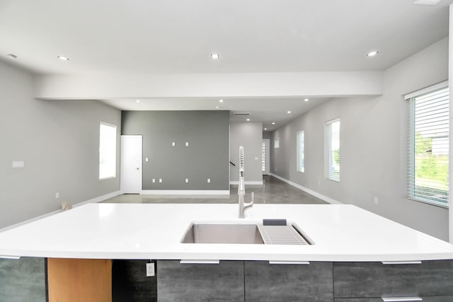 kitchen with a kitchen island with sink, recessed lighting, a sink, open floor plan, and light countertops