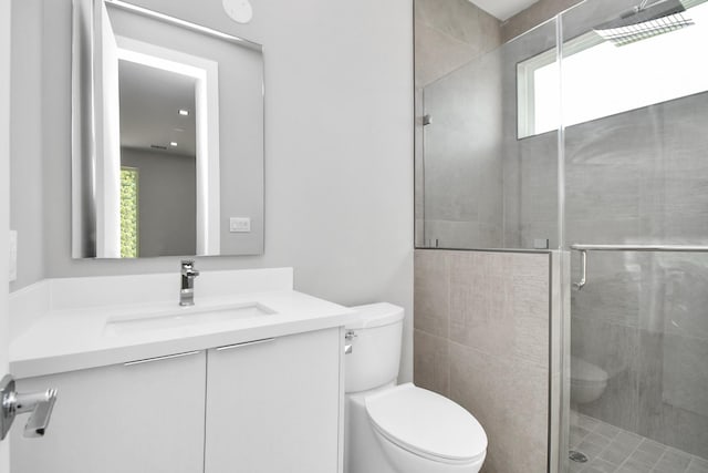 bathroom featuring vanity, a shower stall, and toilet