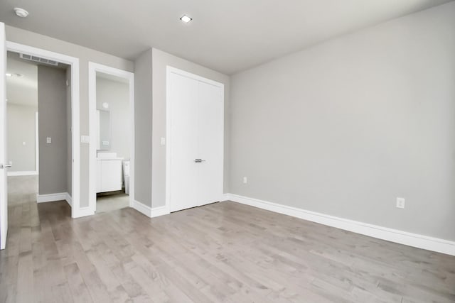 unfurnished bedroom featuring light wood-type flooring, baseboards, visible vents, and a closet