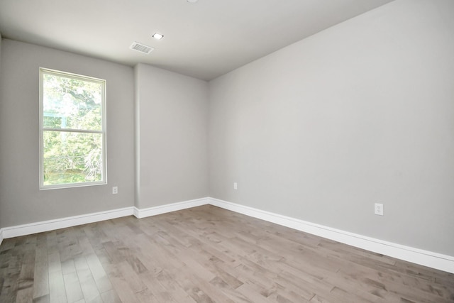 empty room featuring wood finished floors, visible vents, and baseboards