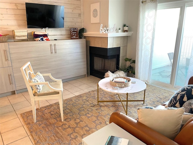 living area with a tile fireplace, wooden walls, and light tile patterned floors