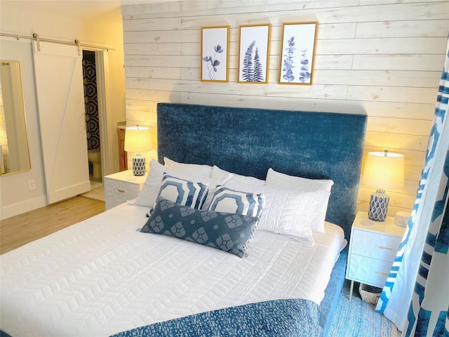 bedroom featuring a barn door, wood finished floors, and wooden walls